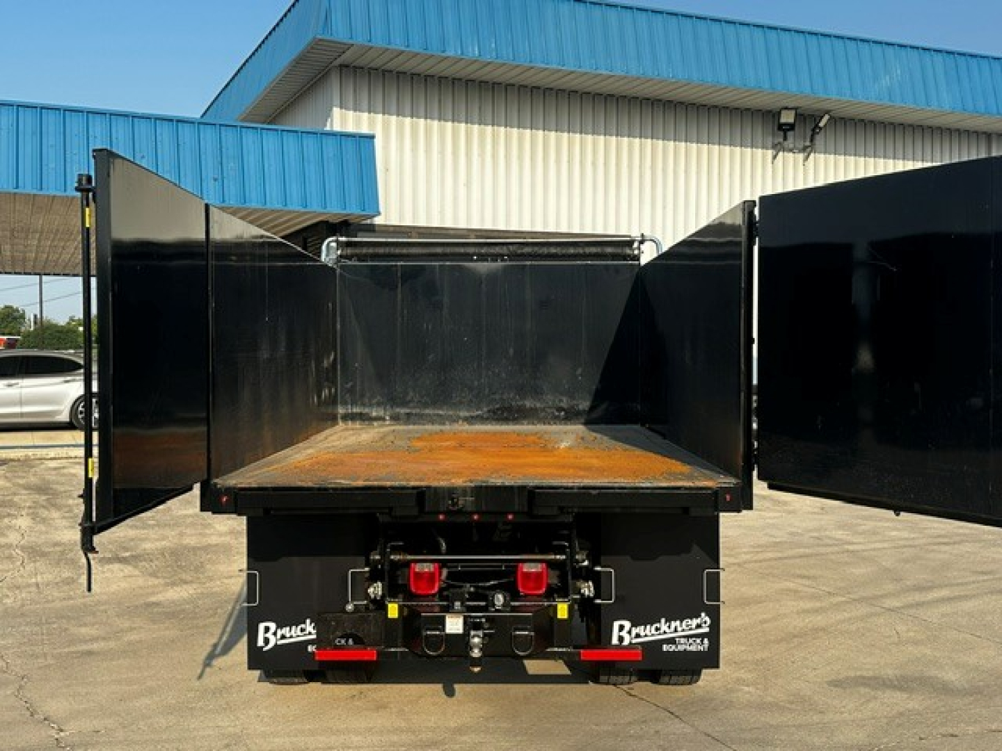 Ford F-750 dump truck bed with open tailgate, visible branding 'Blacks' on mud flaps and a rusty bed floor.