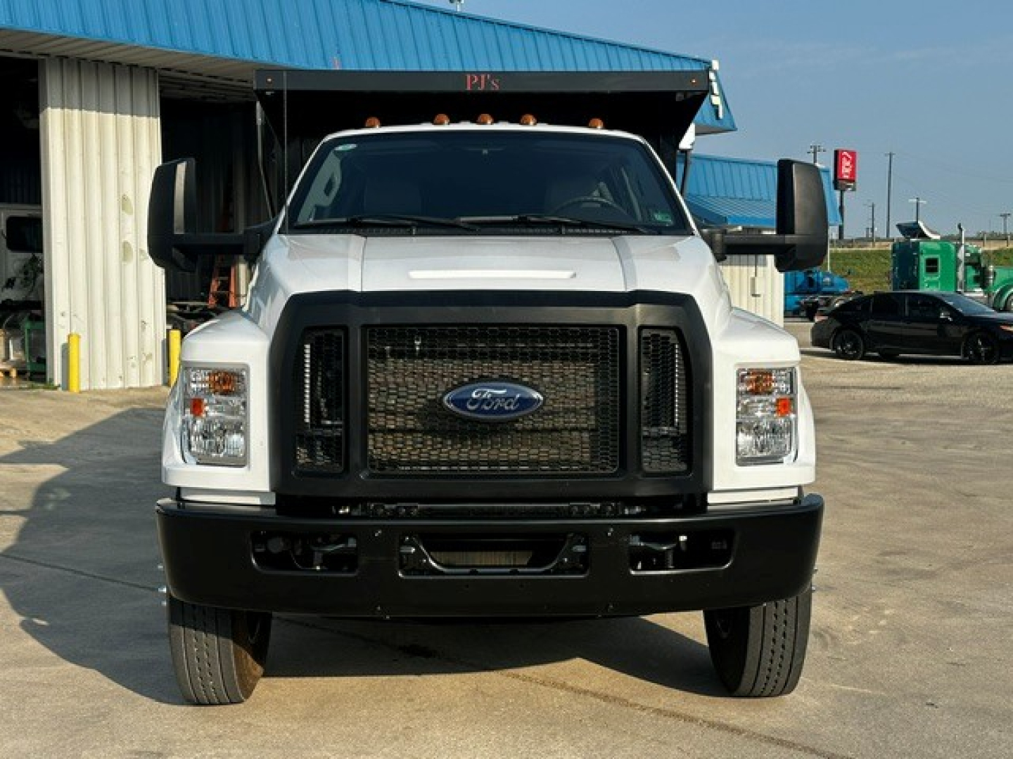 Ford F-750 dump truck front view showing large black grille, Ford emblem, rectangular headlights, side mirrors, and bumper.