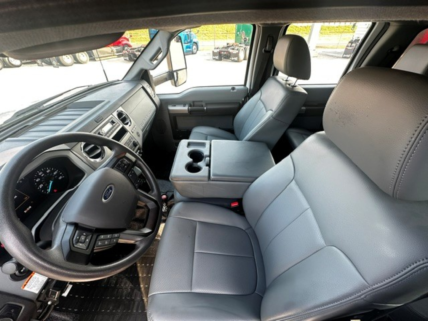 Ford F-750 truck interior showing front seats, steering wheel, dashboard, and center console with cup holders.