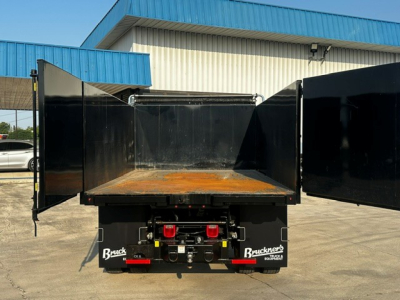 Ford F-750 dump truck bed with open tailgate, visible branding 'Blacks' on mud flaps and a rusty bed floor.