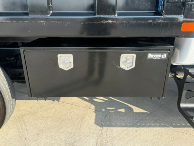 Ford F750 dump truck side view showing black toolbox with two silver latches under cargo bed and Buyers logo on toolbox.