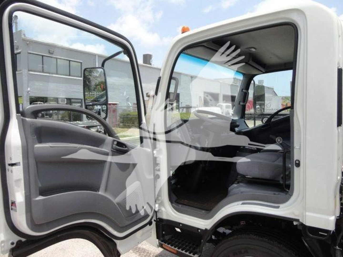 Isuzu NPRR truck cab interior view with open driver door showing seating and dashboard in a rollback truck.