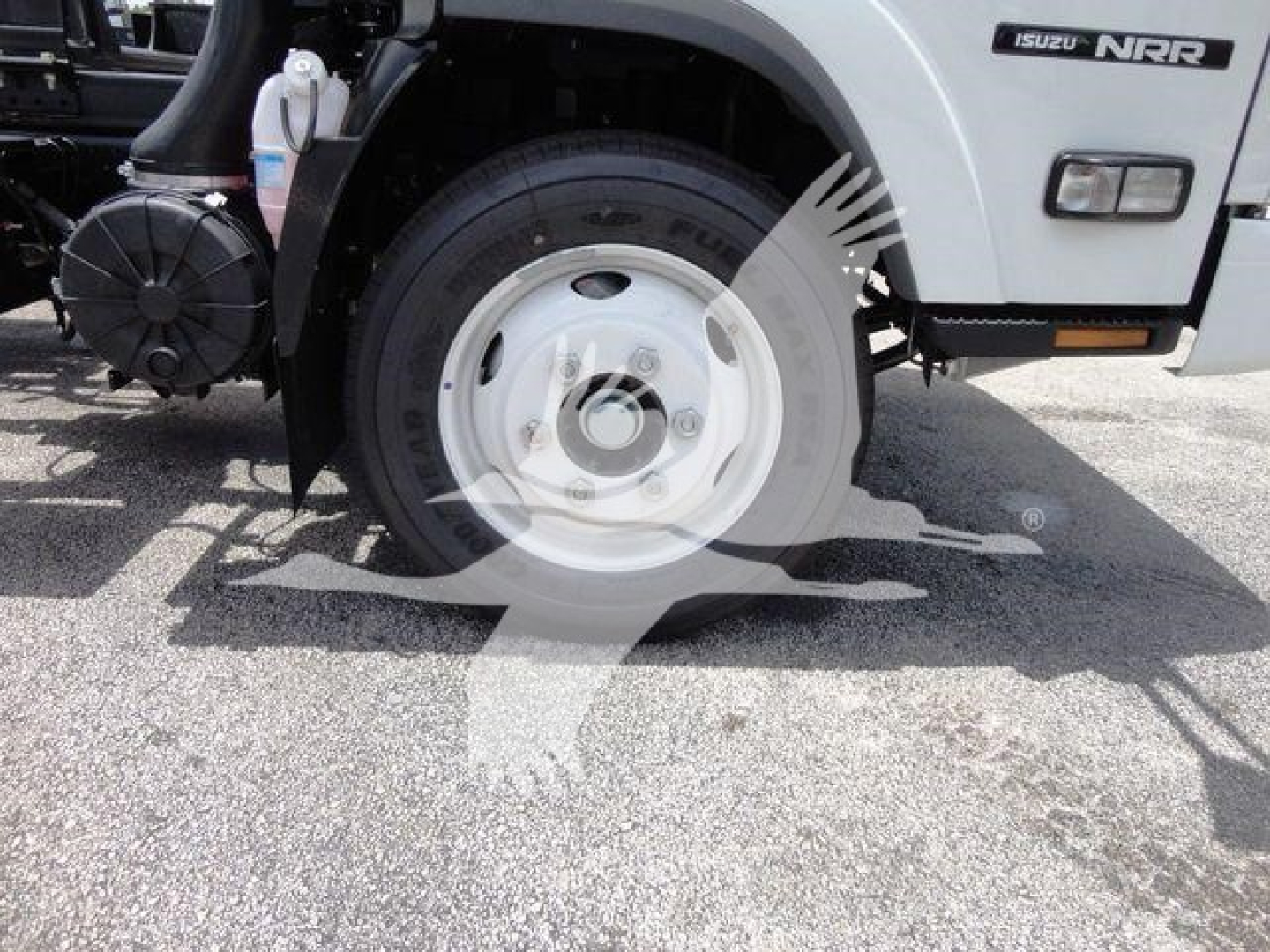 Isuzu NRR rollback truck front wheel and badge visible showing Isuzu NRR branding on the cab with wheel and fender details.