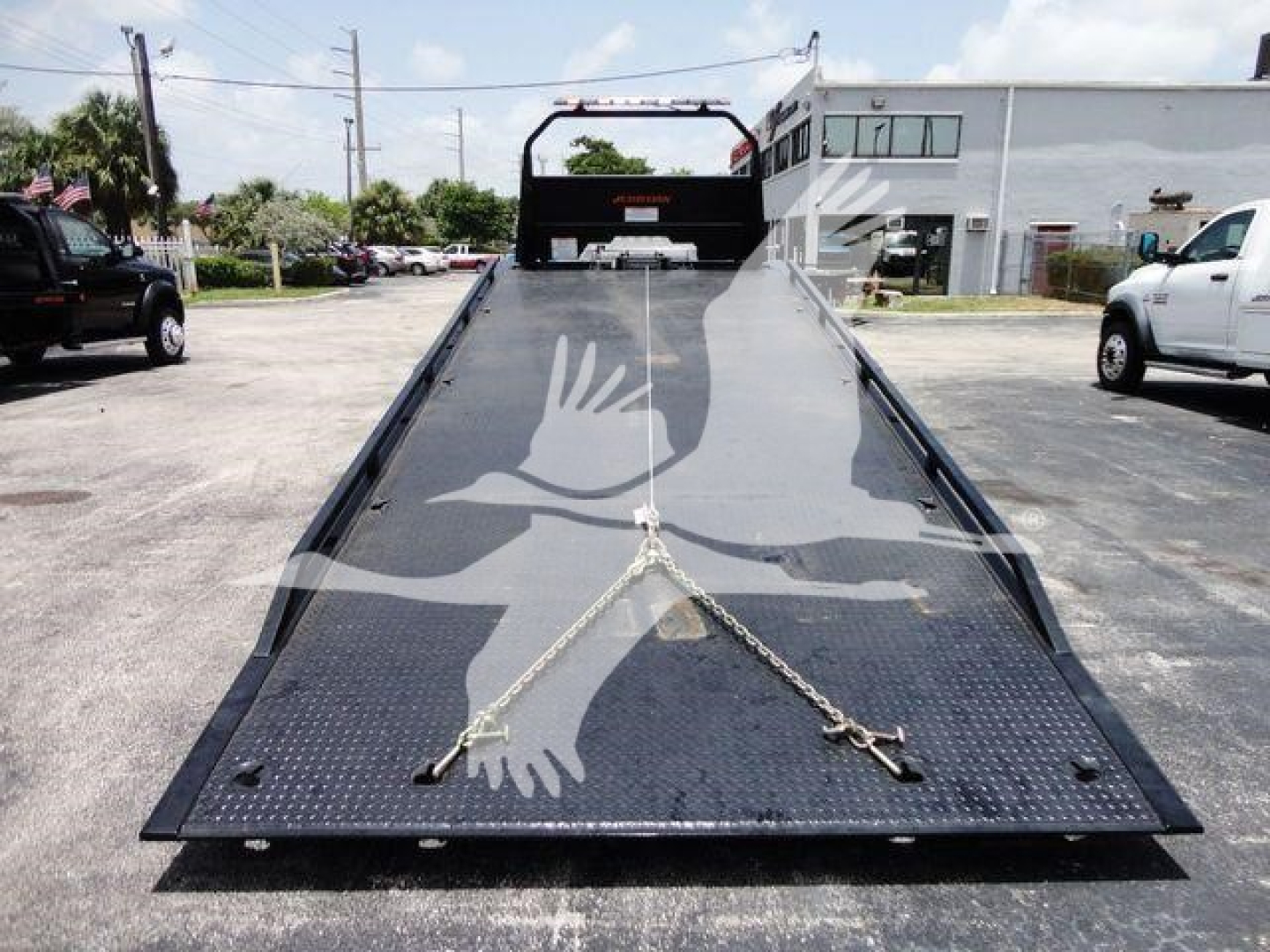 Isuzu NRR rollback truck bed with loading ramp, showing diamond plate deck and tiedown chains.