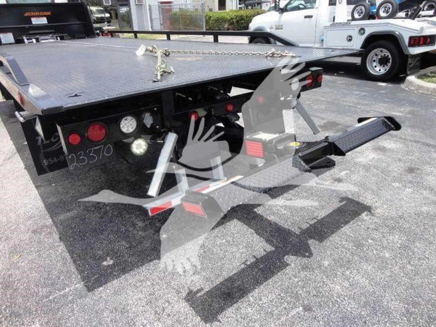 Isuzu NPRR rollback tow truck bed with hydraulic lift and controls. Visible text includes stock number NRRGAS21RRSB and numbers 235370 on left rear. Flatbed with black metal and red taillights.