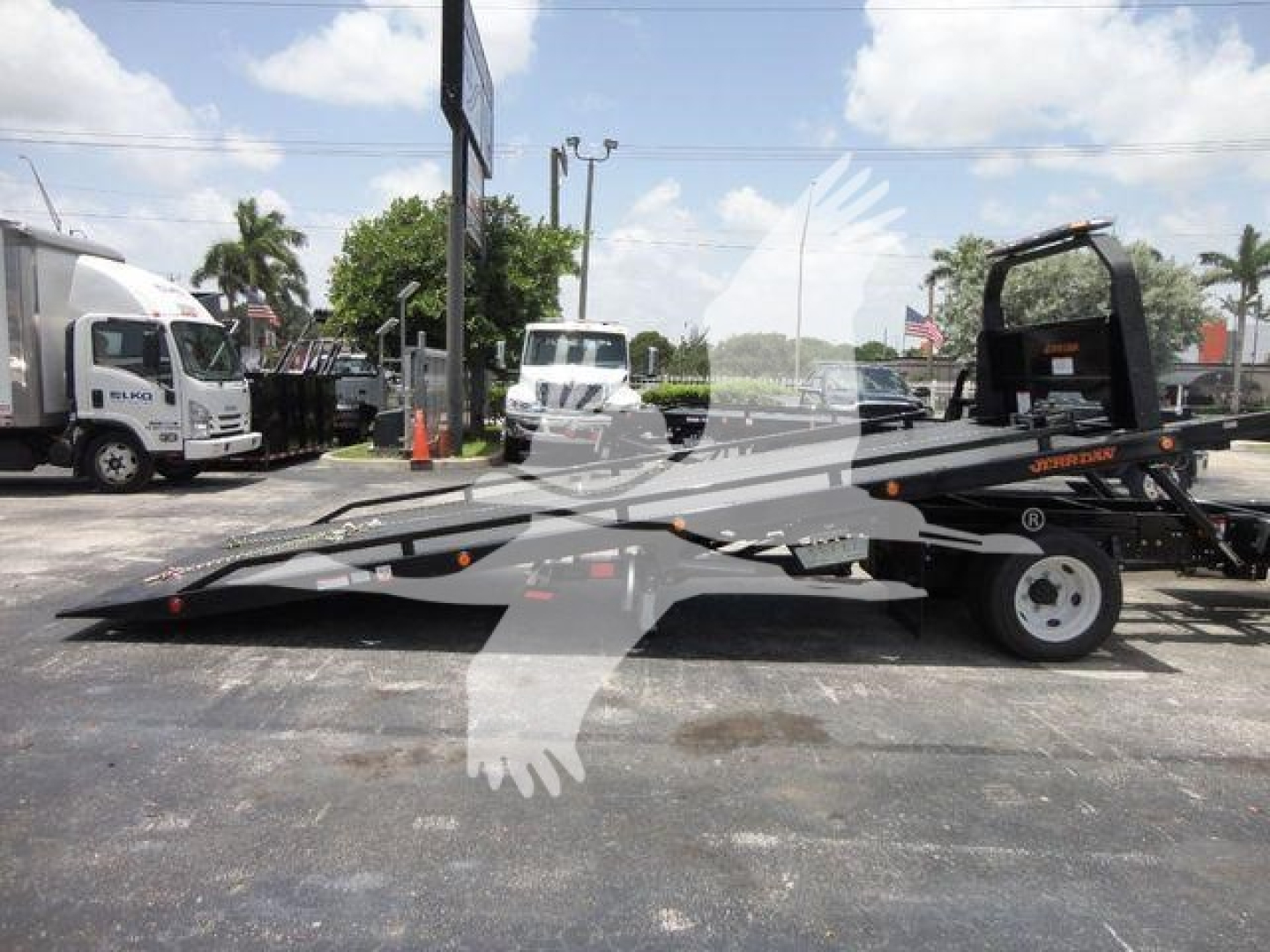 Isuzu NPRR? rollback tow truck with low-profile flatbed and rear wheel, side view showing wheel and hydraulic equipment