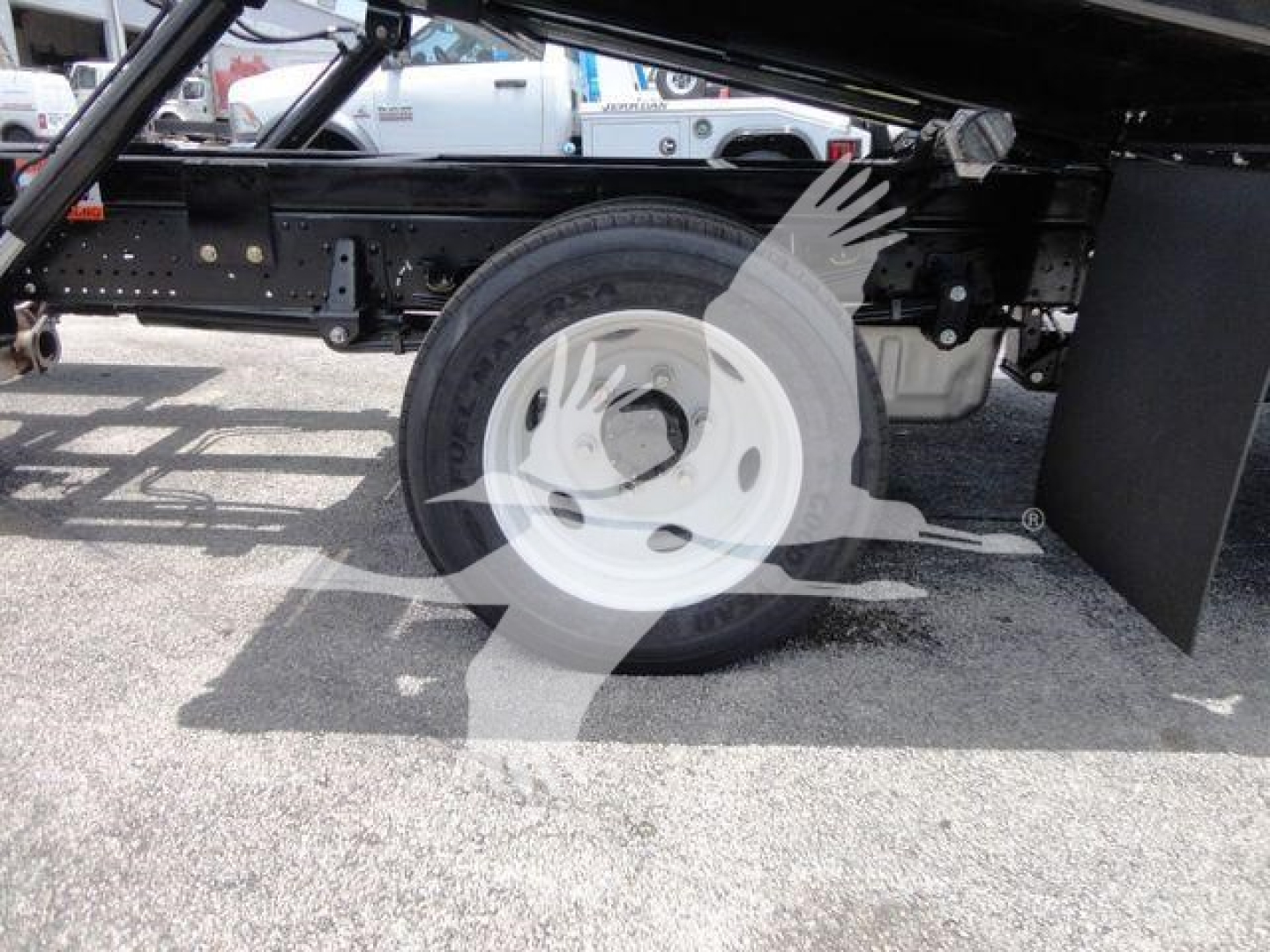 Isuzu NPRR rollback truck undercarriage showing rear wheel and suspension components with white steel wheel.