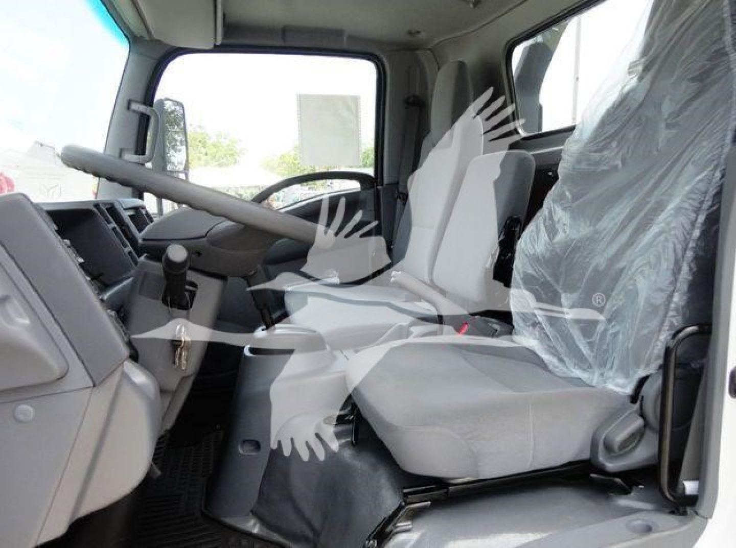 Isuzu NPRR NRR truck cabin interior with driver and passenger seats, steering wheel, and dashboard from side view.
