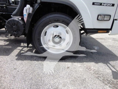 Isuzu NRR rollback truck front wheel and badge visible showing Isuzu NRR branding on the cab with wheel and fender details.