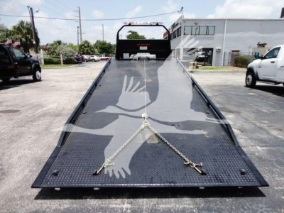 Isuzu NRR rollback truck bed with loading ramp, showing diamond plate deck and tiedown chains.
