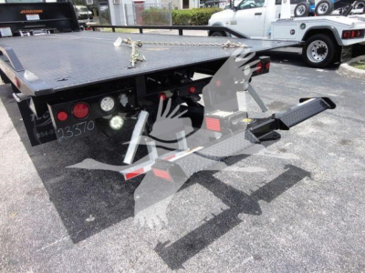 Isuzu NPRR rollback tow truck bed with hydraulic lift and controls. Visible text includes stock number NRRGAS21RRSB and numbers 235370 on left rear. Flatbed with black metal and red taillights.