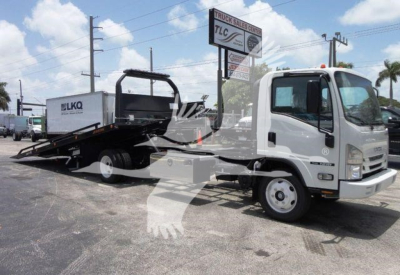 Isuzu NPR/RR truck with a rollback wrecker bed in a dealership lot.
