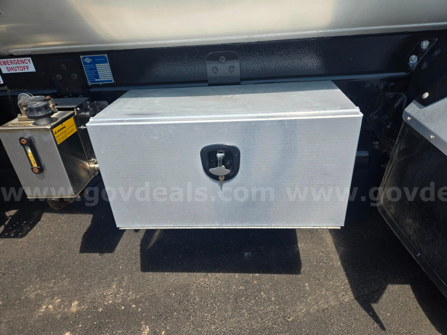 Freightliner M2 fuel or tool box mounted under rear chassis with lockable aluminum box and hydraulic/emergency components nearby.