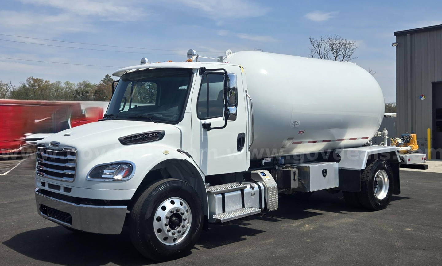 White Freightliner M2 tank truck side view with rounded tank, wheel wells, and front grille; no visible legible labels or specifications on the tank.
