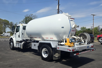Freightliner M2 vacuum/tank truck rear and side view showing large cylindrical tank, rear hose connections, and metal platform with controls