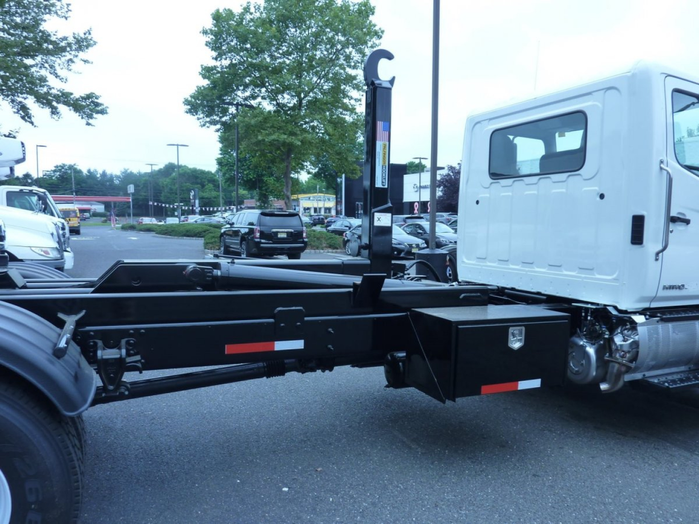 Truck chassis and cab of a 2027 Hino L7 box van truck showing the rear frame and cab-side with a white cab and black chassis.