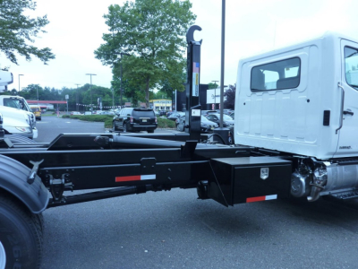 Truck chassis and cab of a 2027 Hino L7 box van truck showing the rear frame and cab-side with a white cab and black chassis.