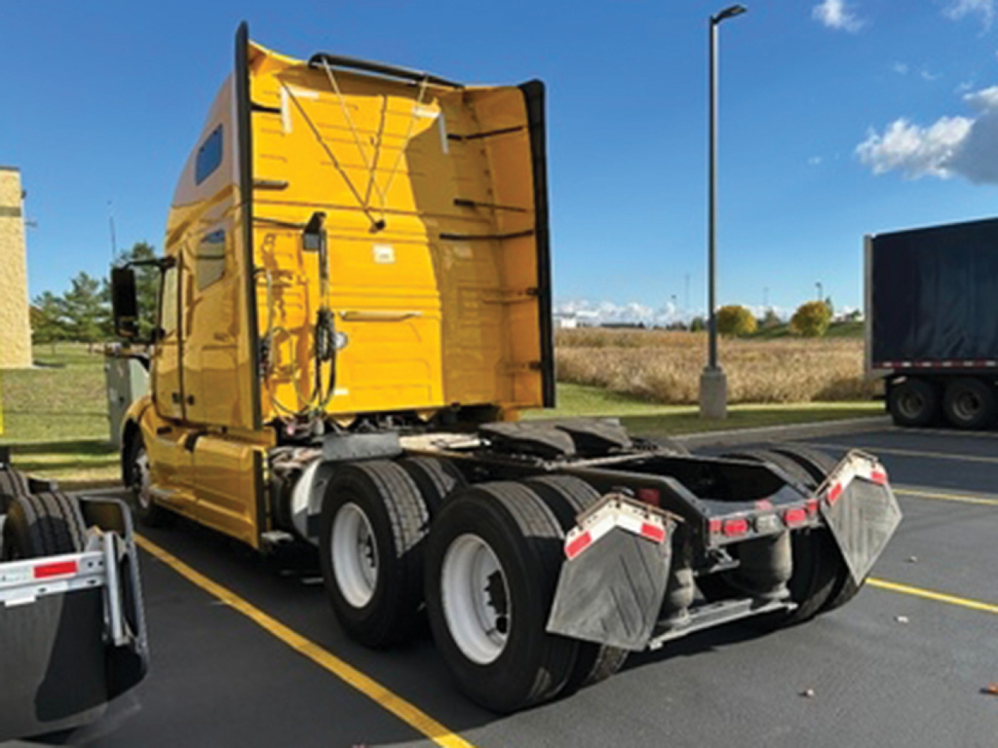 Volvo VNL 760 sleeper tractor rear view showing fifth wheel and dual rear axles with chrome rims and yellow cab.