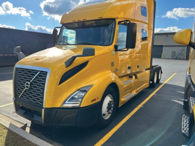 Volvo VNL 760 sleeper tractor in yellow front-left view showing grille, headlights, and cab details.