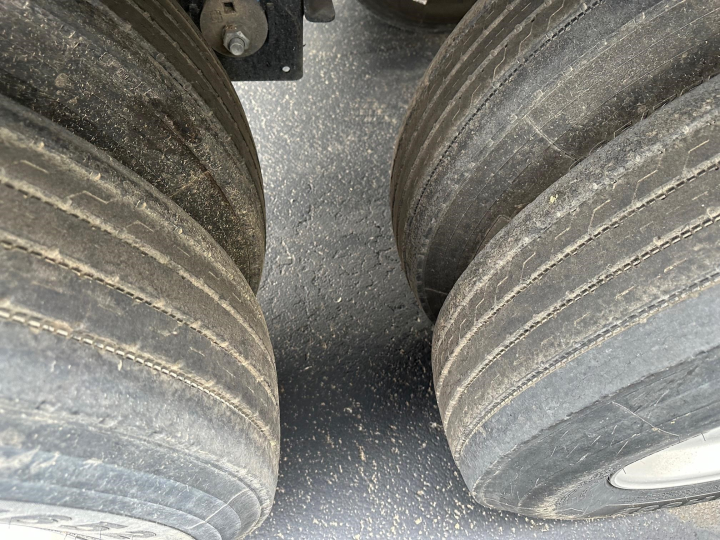 Trailer axle view showing two large dual tires with road grime and grooves; part of a Timpte hopper trailer.