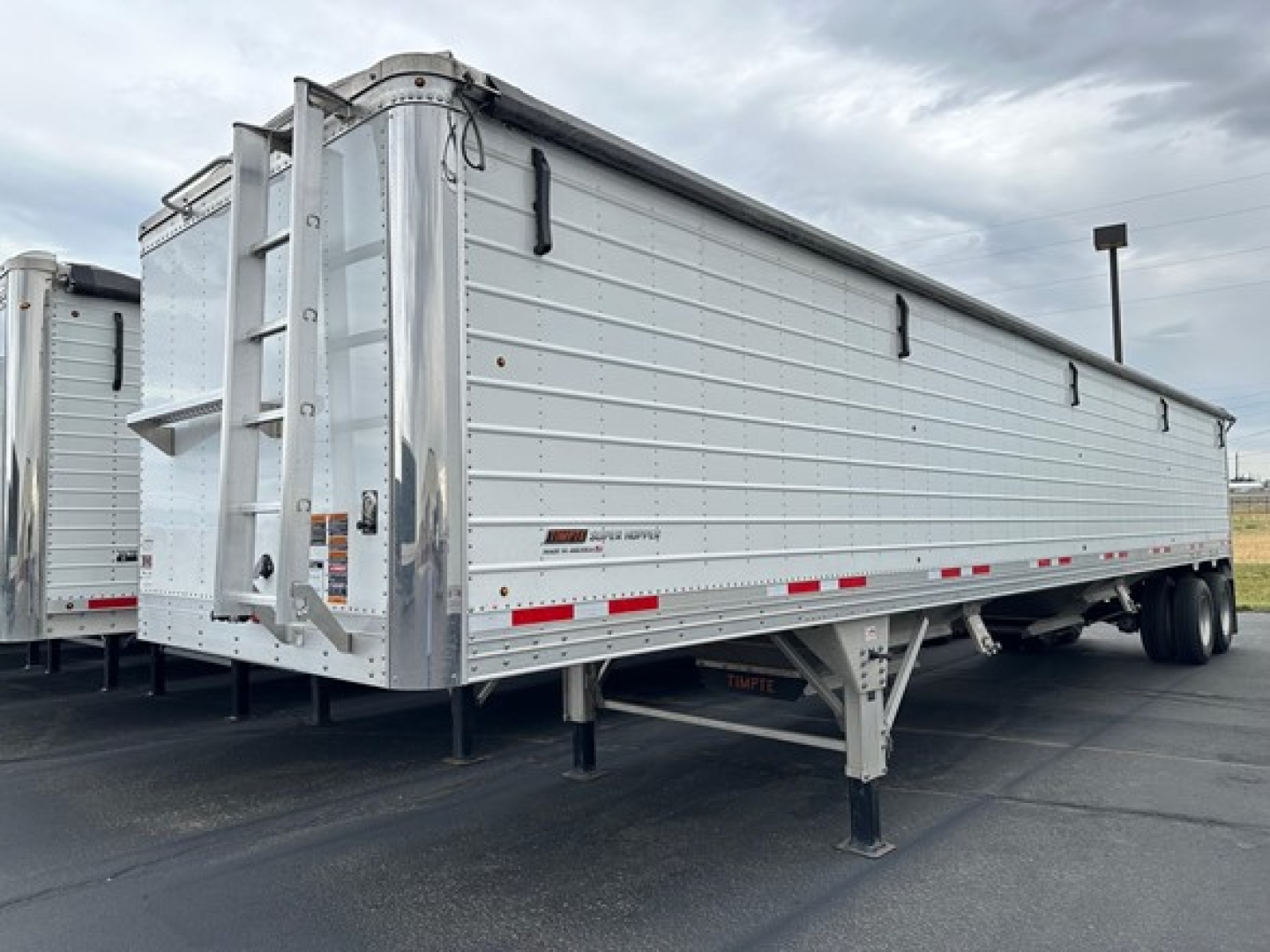 Timpte Super Hopper trailer in side and rear view showing aluminum hopper with ladders, undercarriage, and dual rear axle.