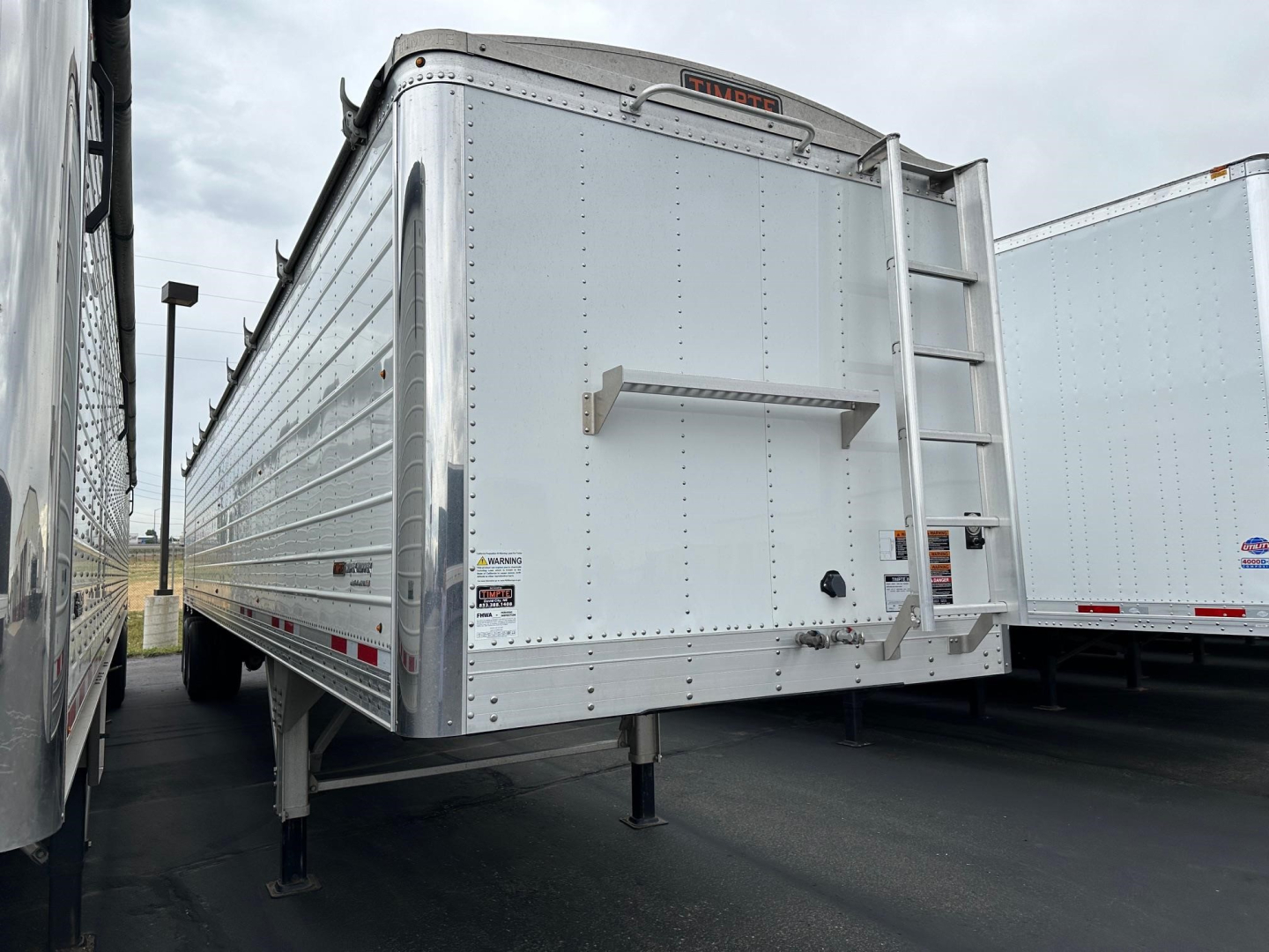 Timpte Super Hopper trailer side and rear view showing aluminum panels and fold-down ladder mounting at rear.