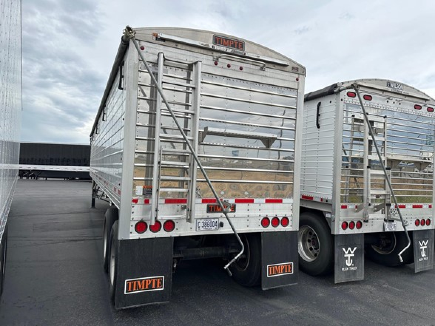 Trailer rear view showing Timpte Super Hopper with metal sides, rear doors, bumper guards, and mud flaps; stock number plate and VIN visible