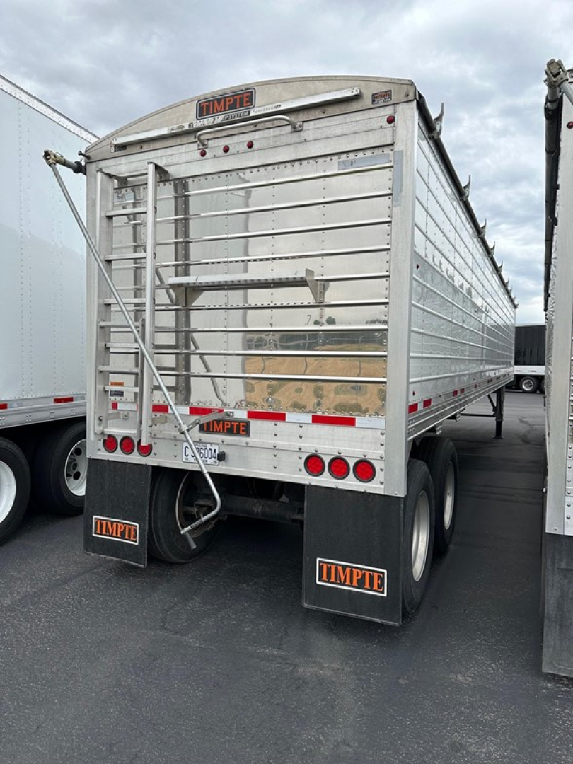 Timpte Super Hopper trailer rear view showing metal side panels, ladder, taillights, rear bumper, and TIMPTE mudflaps.