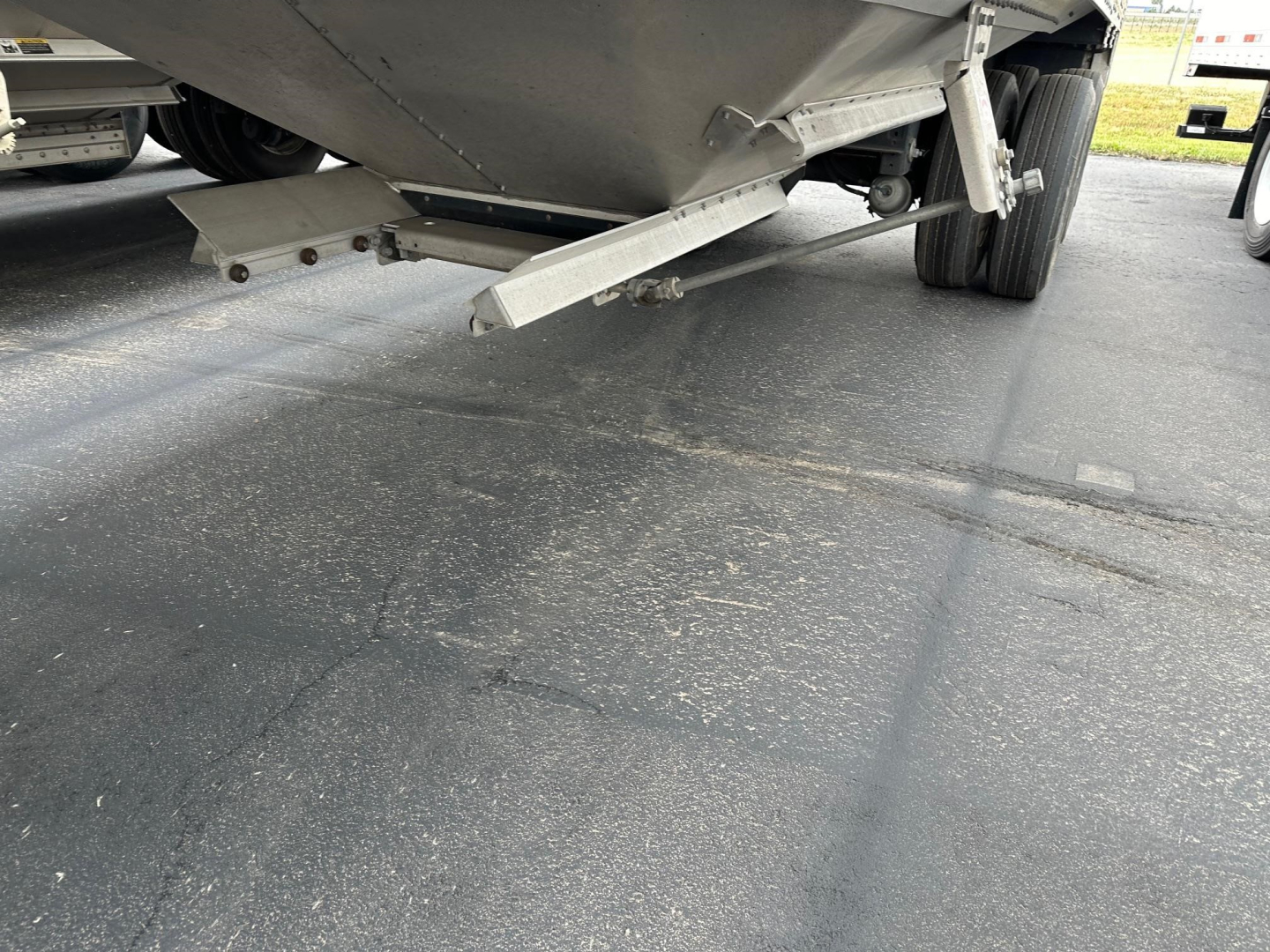 Trailer underside showing metal pour/step and reinforcement with wheel in background.