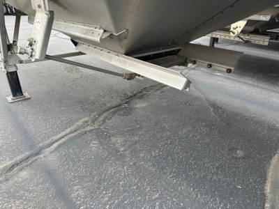 Hopper trailer underside showing support legs and steel framework with hitch area and underside beam.