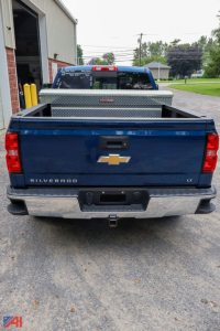 Chevrolet Silverado 1500 LT crew cab pickup truck rear view with diamond plate toolbox in bed and Chevrolet bowtie emblem.