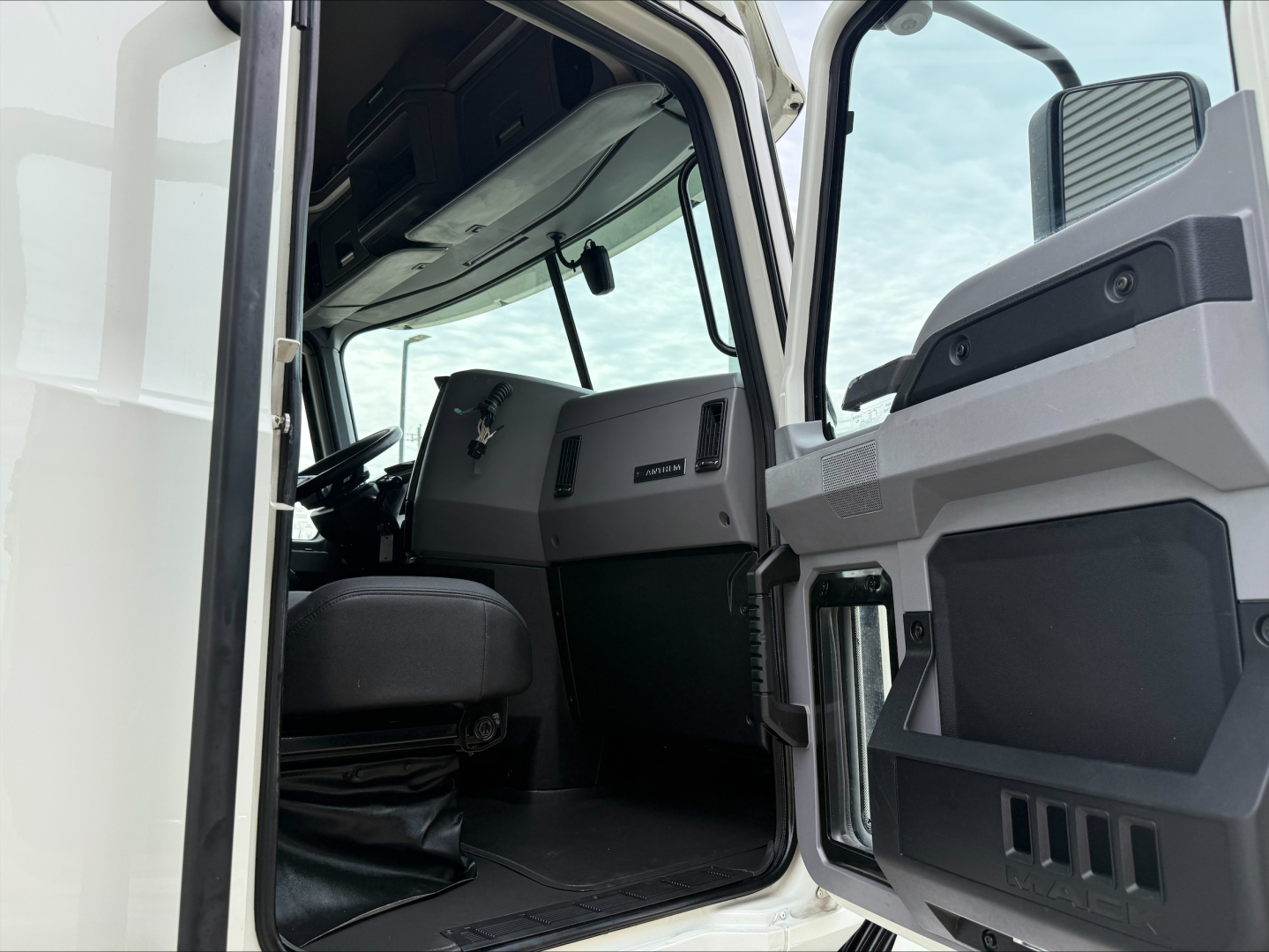 Cab interior of a 2020 Mack Anthem truck showing driver seat, dashboard, and open door with storage compartments.