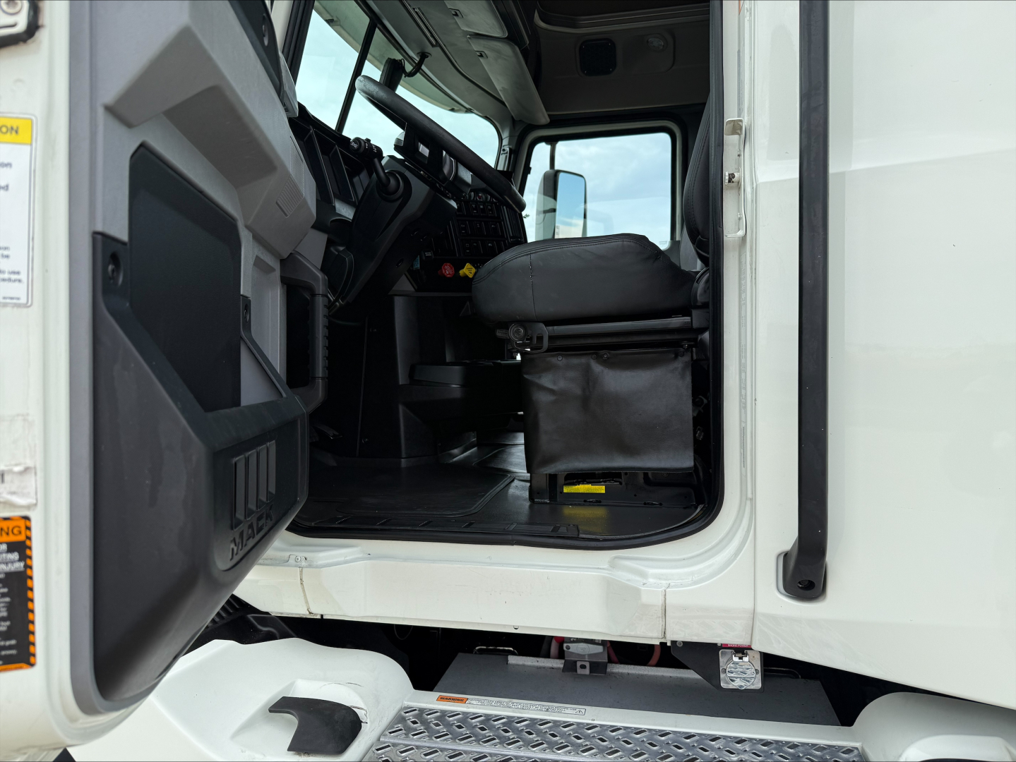 Truck cab interior of a 2020 Mack ANTHEM from the driver’s door side showing seating and steps.