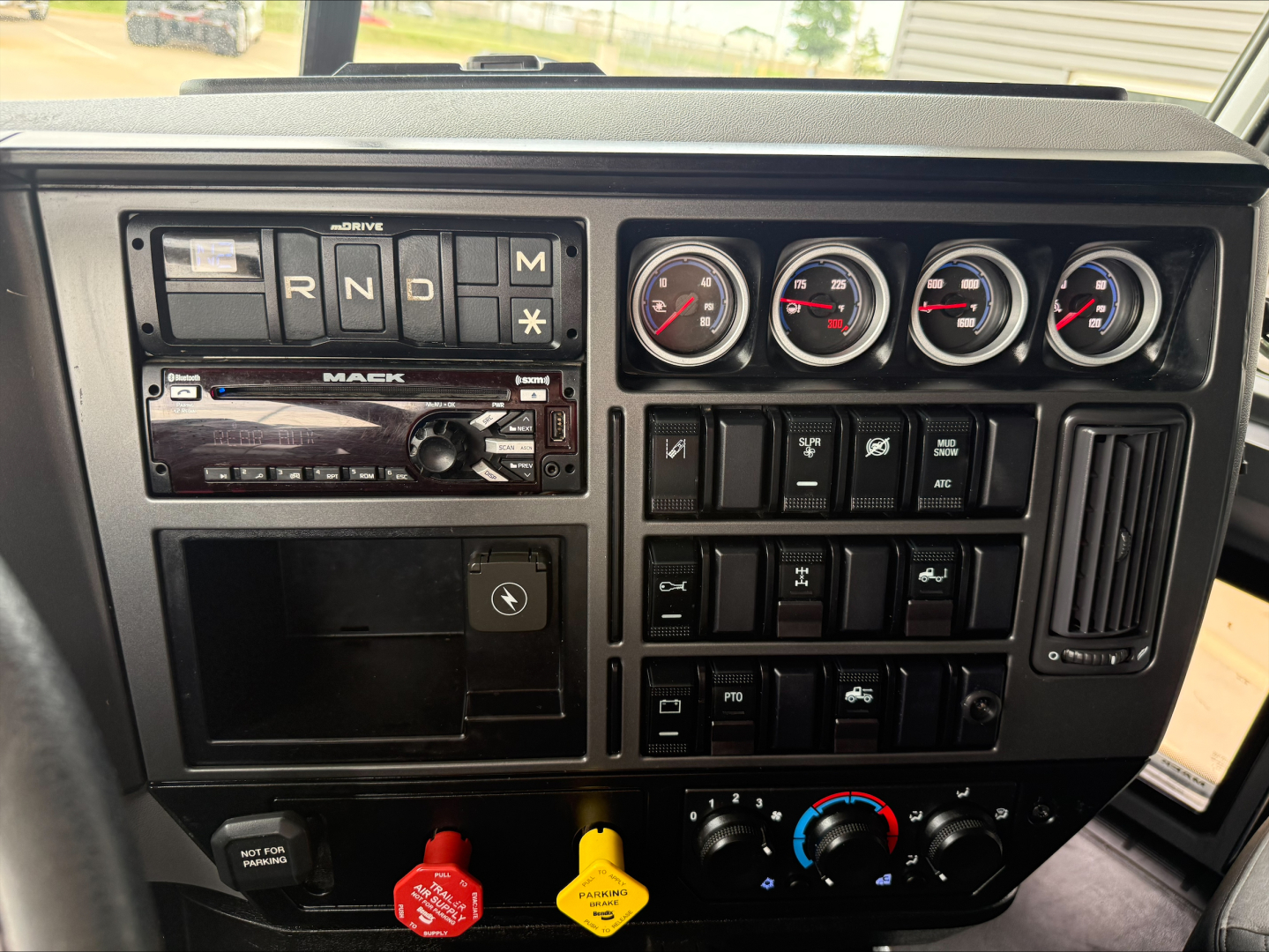 Mack ANTHEM truck dashboard showing drive selector, gauges, radio, and climate controls.