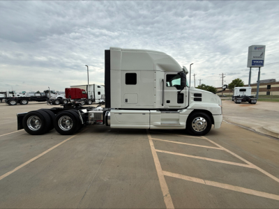 2020 Mack Anthem conventional sleeper tractor side view showing cab, chassis, and dual rear axles with fuel tanks and exhaust under a cloudy sky.