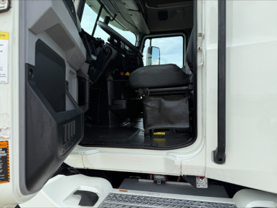 Truck cab interior of a 2020 Mack ANTHEM from the driver’s door side showing seating and steps.