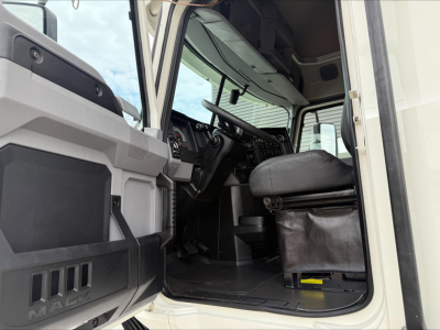 Truck cabin interior of a 2020 Mack Anthem, shown from the driver side with open door; emphasis on the steering wheel, dashboard, and driver's seat.