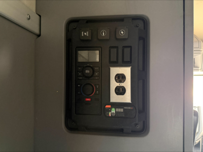 Panel with switches and control module inside Mack ANTHEM dashboard showing buttons, a small display, and a two-outlet module.