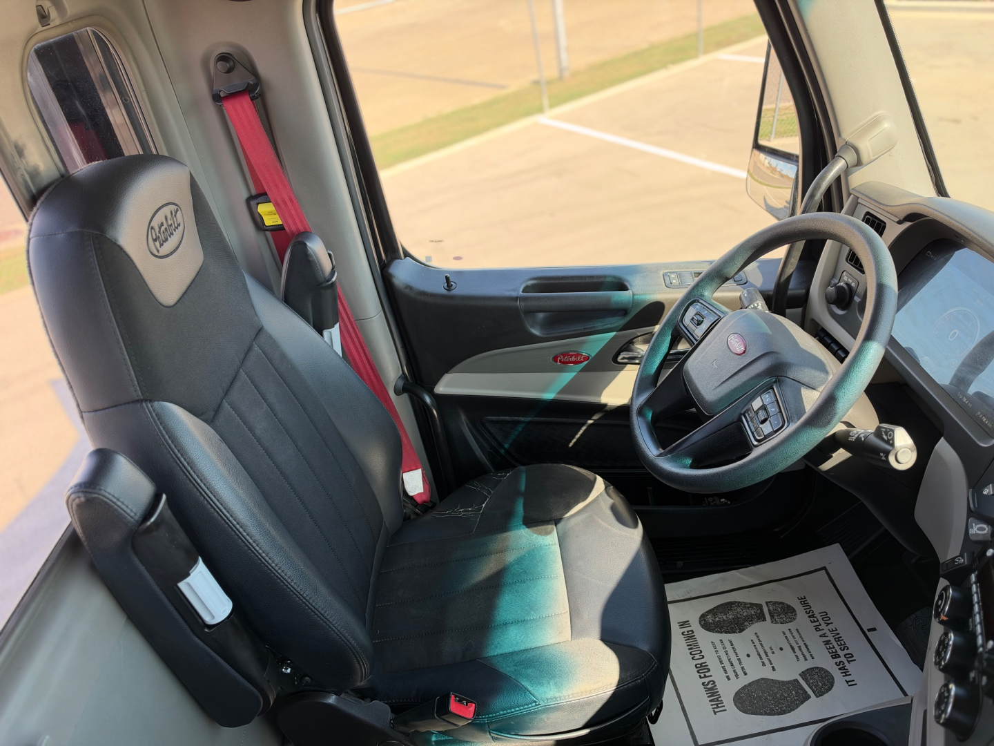 Peterbilt 579 truck cab interior showing driver seat with steering wheel and dashboard from the left front, typical cab layout.