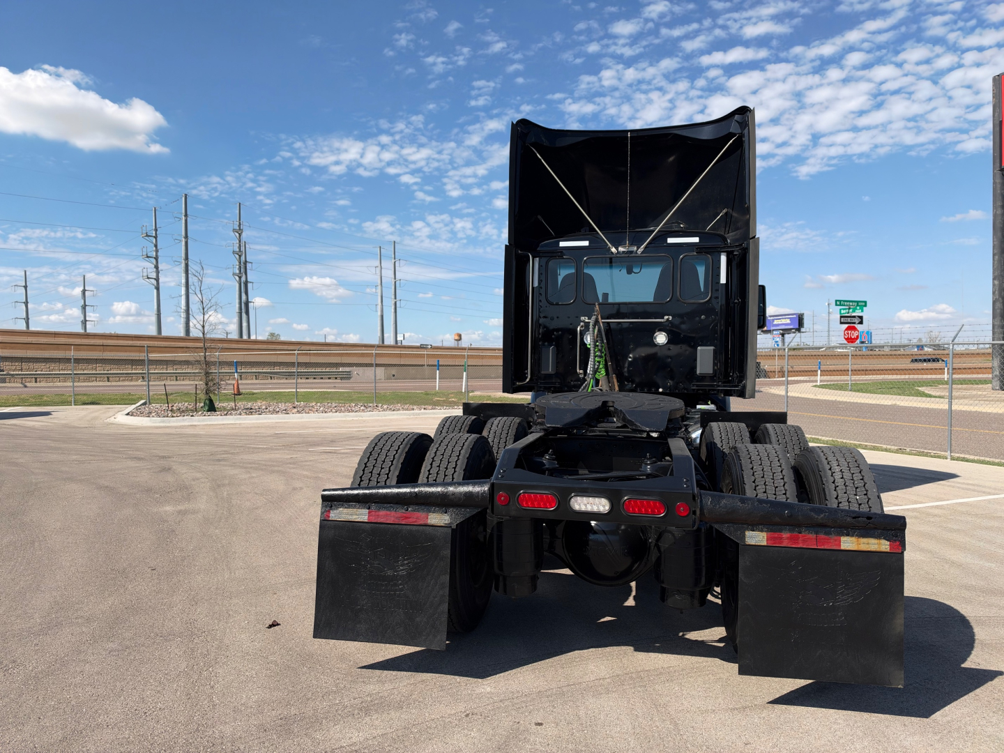 Peterbilt 579 conventional daycab rear view showing fifth wheel area and dual rear axles in a parking lot