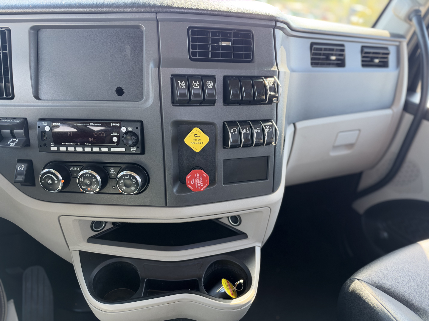 Peterbilt 579 truck dashboard/console showing various switches and controls, with circular climate controls and storage compartments.