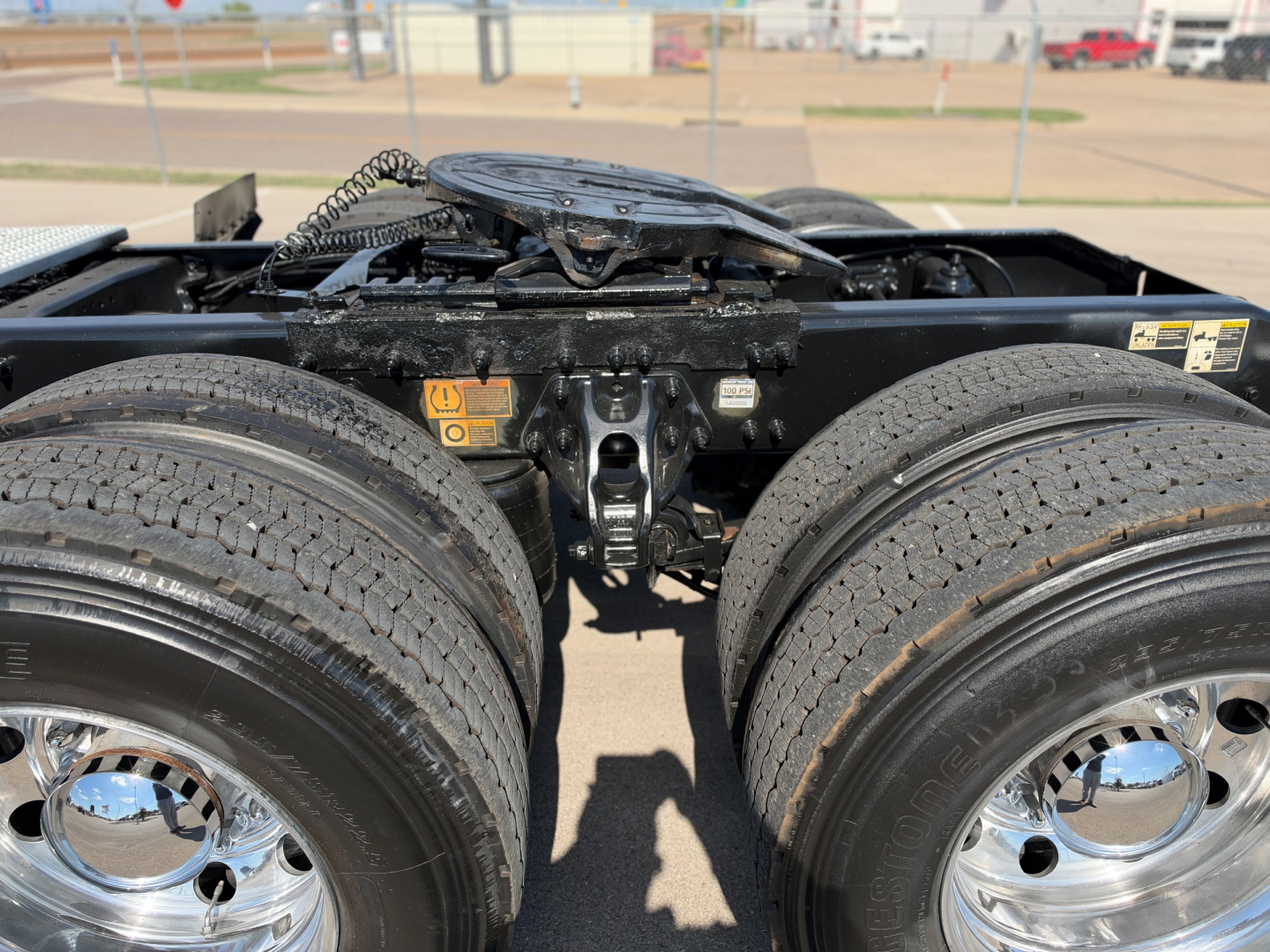 Peterbilt 579 tractor truck rear view showing fifth wheel and dual rear axles with dual dual tires, chrome hubcaps, and undercarriage components.