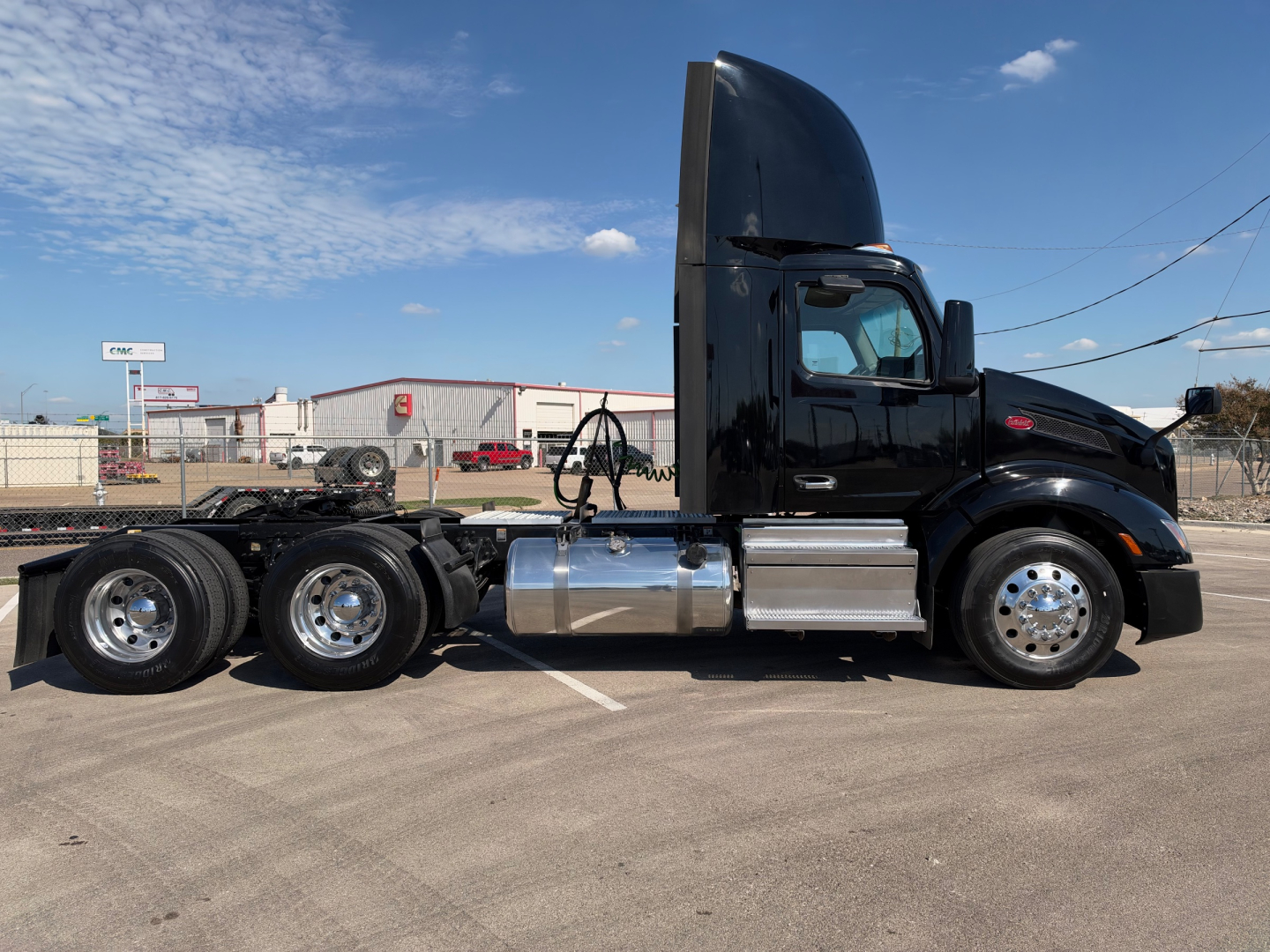 Peterbilt 579 tractor in black, side view showing chrome fuel tanks and chassis with sleeper cab, 6x4 configuration.