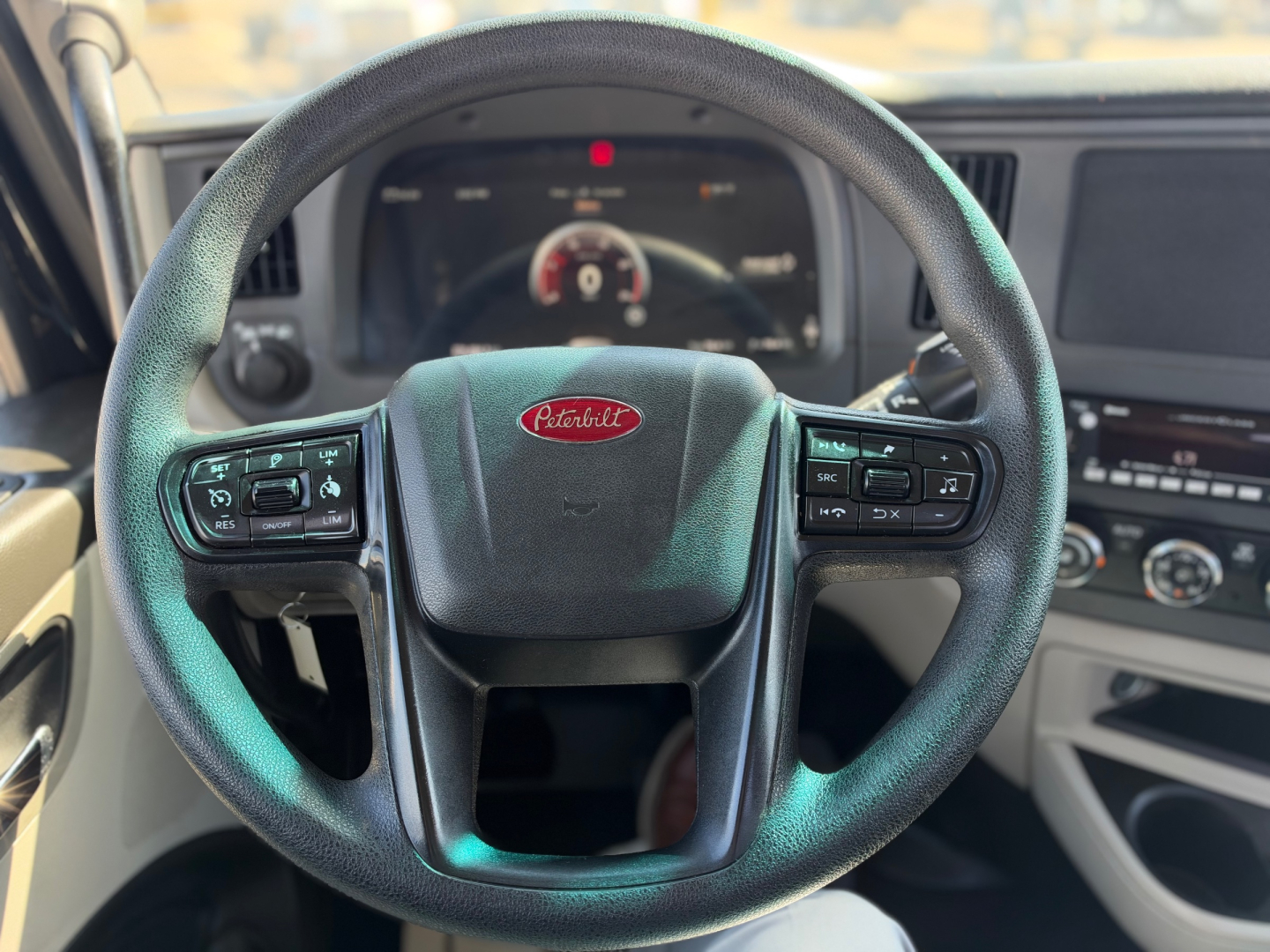 Peterbilt steering wheel and dashboard in a 2022 Peterbilt 579, with visible controls on the steering wheel and instrument cluster in the background.