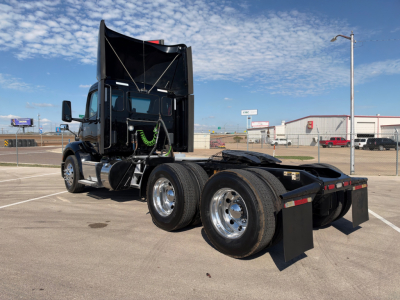 Peterbilt 579 conventional daycab tractor, triple rear axles, black paint, chrome wheels, fuel tanks, and fifth wheel visible.