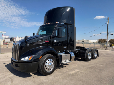 Peterbilt 579 conventional daycab tractor in black, side view showing cab roof exhaust stack, chrome fuel tanks, and dual rear axles; no visible badges or text on the image.