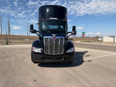 Peterbilt 579 conventional daycab truck facing forward showing grille and headlights, blue exterior, clear sky.