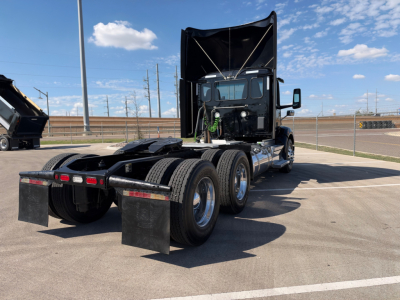 Peterbilt 579 in-service conventional daycab tractor shown from rear-left angle with raised hood and dual rear axles. No visible text on decals or labels.