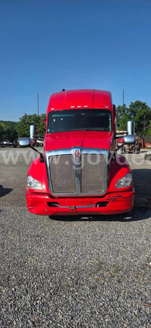 Front view of a red Kenworth truck showing grille, headlights, and chrome bumper. No visible text legible on components.