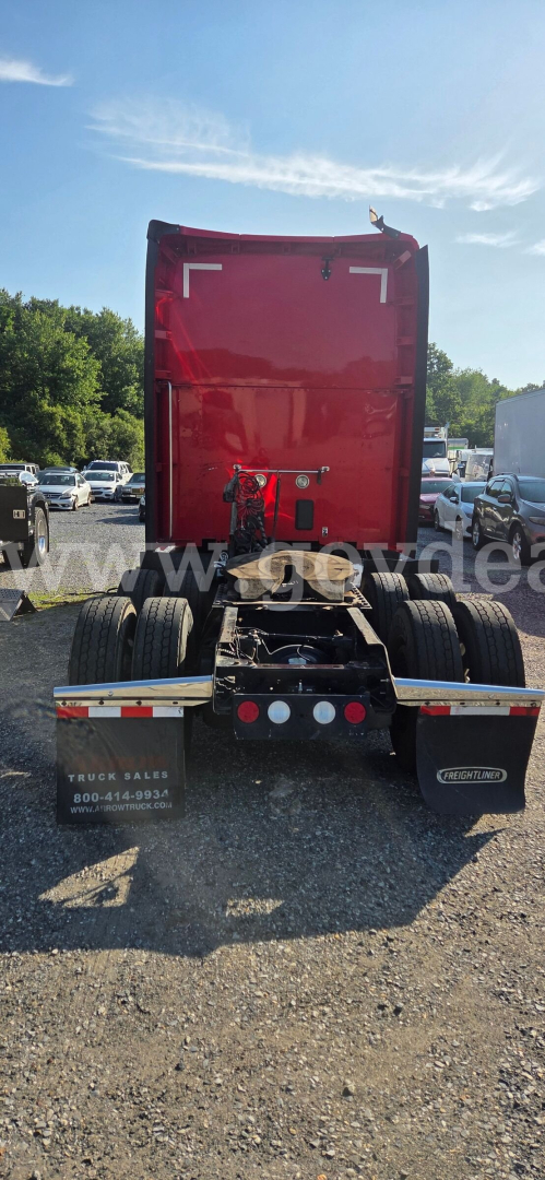 Rear view of a red Kenworth T680 tractor with fifth wheel and dual rear axles, stock plate area visible, in a lot.